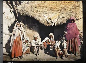 Image représentant Un groupe de villageois (ou famille ?) à l'entrée d'une maison ; l'homme assis fume le "Hukka"
