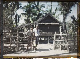 Image représentant Un vieil homme, une jeune femme et un enfant devant une maison sur pilotis