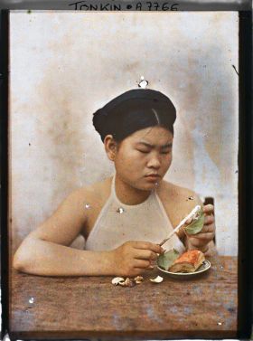 Image représentant Une jeune femme enduisant de chaux la feuille de bétel lors de la troisième phase de la confection d'une chique de bétel