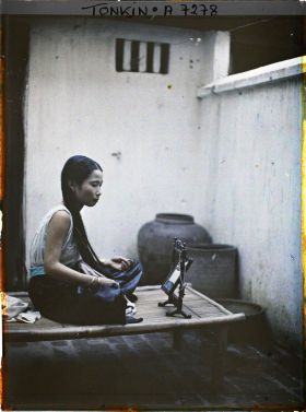 Image représentant Une jeune élégante de classe aisée à sa toilette, assise sur une banquette en bambou dans la cour intérieure de son habitation