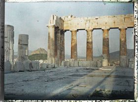 Image représentant Sur l'Acropole, le Parthénon. Vestiges de la colonnade extérieure côté est et derrière eux façade est de l'Acropole, la ville à ses pieds et le Mont Lycabette ("vue plongeante")