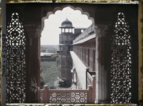 Image représentant Tour extérieure surmontée d'un chatri, vue d'une fenêtre encadrée de jalis (dentelle de pierre formant claustra) dans le fort Rouge (Lal Qila)