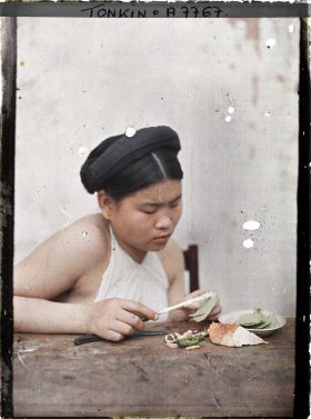 Image représentant Une jeune femme enduisant de chaux la feuille de bétel lors de la troisième phase de la confection d'une chique de bétel