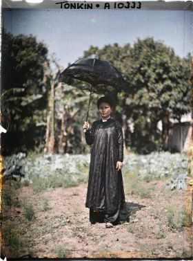 Image représentant Une femme de classe aisée, s'abritant sous une ombrelle noire bordée de dentelle