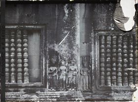 Image représentant Un relief d'apsaras sculpté entre deux fenêtres à balustres d'une galerie