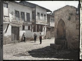 Image représentant Trois hommes devant des maisons modestes