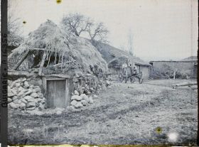 Image représentant Un silo (?) recouvert de chaume, bâtiments de ferme et trois enfants sur une carriole