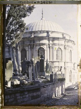 Image représentant Dans le cimetière de l'Eyüp Sultan Camii, un gros mausolée et des tombes le long d'une rue pavée