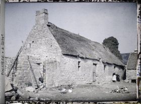 Image représentant Deux femmes devant un bâtiment de ferme couvert de chaume