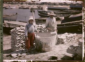Image représentant Un couple d'ostréiculteurs recouvrant de chaux une tuile pour recueillir les huîtres