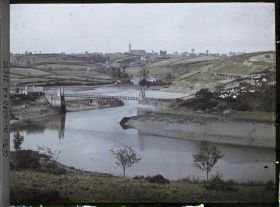 Image représentant La passerelle Saint-François sur le Guindy ; à l'arrière-plan, le village de Plouguiel