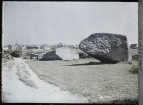 Image représentant Le Grand Menhir brisé ; à l'arrière-plan, le village de Locmariaquer