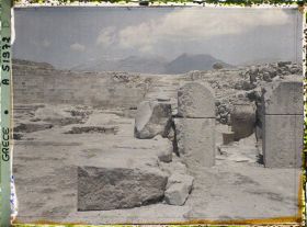 Image représentant Le palais. Dans la cour occidentale, au fond, l'escalier nord. En premier plan, à droite, extrémité des magasins avec un phitos (jarre)