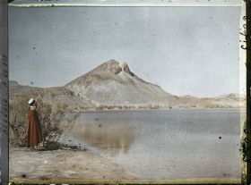 Image représentant Un homme se tient sur la rive du lac ; à l'arrière-plan, les pitons de marne verte