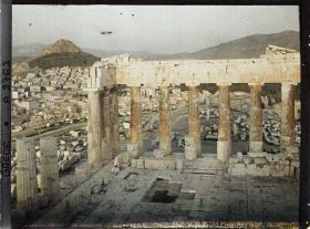 Image représentant Sur l'Acropole, le Parthénon. Vestiges de la colonnade extérieure côté est et derrière eux façade est de l'Acropole, la ville à ses pieds et le Mont Lycabette (vue plongeante)