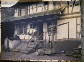 Image représentant France Alsace, Strasbourg, Langolsheim : un type de grande ferme rurale de la Campagne Strasbourgeoise l'entrée de la maison du maître, l'escalier, la pompe du puits et la Cave.