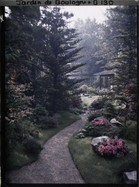Image représentant Étroit chemin ombragé, orné de pierres et d'azalées, menant à la maison ouest du " village japonais "