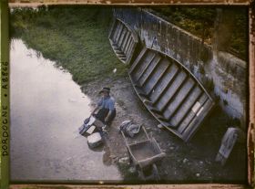 Image représentant Jeune femme lavant son linge au bord de la Dronne, des barques plates derrière elle