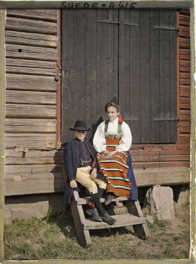 Image représentant Jeune garçon et femme assis devant la porte d'une grange