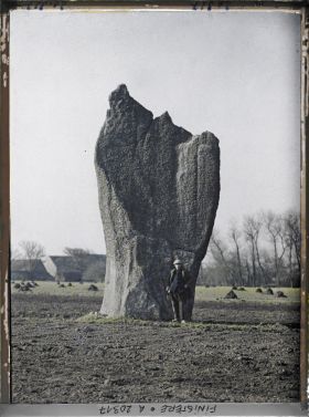 Image représentant Devant l'un des deux menhirs de Kerscaven, dit le menhir de l'Evêque, un homme pose pour indiquer l'échelle du mégalithe