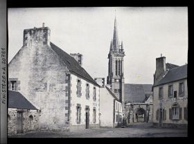 Image représentant Une place du village et l'église Saint-Jean-du-Doigt derrière la porte monumentale du cimetière