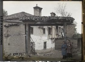 Image représentant Maison à travers une porte de bois s'appuyant sur des montants de brique crue avec deux enfants