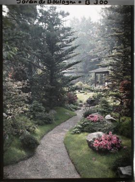 Image représentant Étroit chemin ombragé, orné de pierres et d'azalées, menant à la maison ouest du " village japonais "