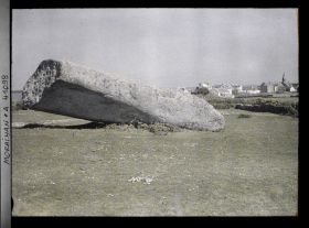 Image représentant Le plus gros des quatre fragments du Grand Menhir brisé ; à l'arrière-plan, le village de Locmariaquer