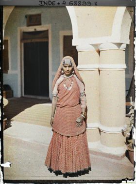 Image représentant Une femme debout à l'entrée d'une maison ou dans une cour intérieure