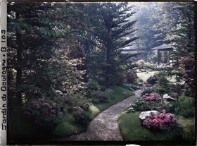 Image représentant Étroit chemin ombragé, orné de pierres et d'azalées, menant à la maison ouest du " village japonais "