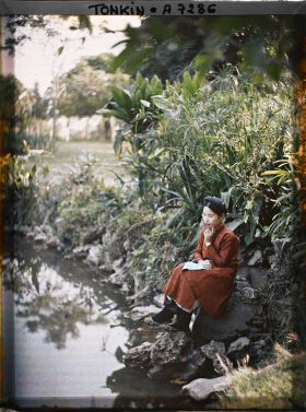 Image représentant Une jeune femme de classe aisée, assise au bord d'une pièce d'eau dans un jardin public