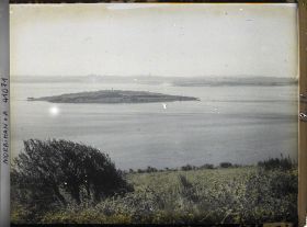 Image représentant L'îlot d'Er Lannic où l'on distingue plusieurs menhirs des cromlechs, vue prise depuis le tumulus de Gavrinis