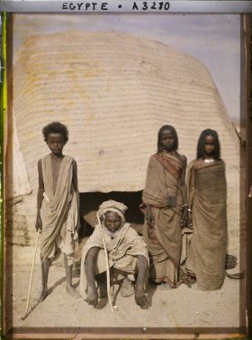 Image représentant Trois enfants et un vieillard  null bishari posent pour l'opérateur devant l'entrée d'une habitation