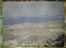 Image représentant Panorama depuis le mont Cynthe en direction du nord-ouest : la ville-haute, puis au bord de la mer, la ville-basse et le port. Au fond, les îles de Syros et plus loin Tinos