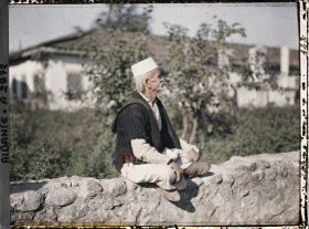 Image représentant Vieil homme sur le muret d'un cimetière