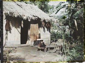 Image représentant Jeune femme fendant du bois devant une habitation