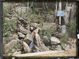 Image représentant Un homme, de dos, appuyé aux rochers à la source d'un petit cours d'eau, au bord de la route gravissant le massif du Tam-dao (" Trois Sommets ")