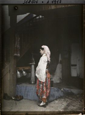 Image représentant Une fillette serbe en costume traditionnel dans la cour d'une maison