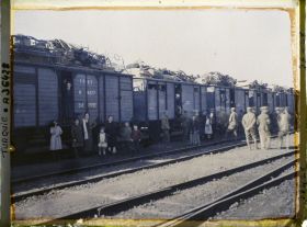 Image représentant Grecs quittant la ville, au pied d'un train chargé de mobilier
