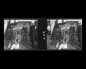 Image représentant A bord du Mongolia, une passagère des 1eres classes recouverte de guirlandes de fleurs, devant Maurice Levy