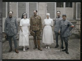 Image représentant Médecins français entourant un officier américain, Madame Mireille Andrieu coiffée d'un voile d'infirmière bleu et Rose Georgette Saint-Paul, infirmière major
