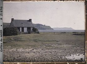 Image représentant Une maison sur la côte ; à l'arrière-plan, la pointe du Château et l'île Tomé