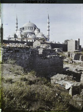 Image représentant La Süleymaniye Camii ("mosquée de Soliman le Magnifique") ; au premier plan des bâtiments couverts d'un toit en toile coincée par des pierres.