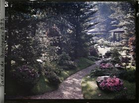 Image représentant Étroit chemin ombragé, orné de pierres et d'azalées, menant à la maison ouest du " village japonais "