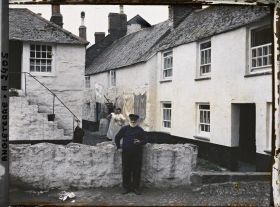 Image représentant Un pêcheur fumant la pipe posant devant des habitations