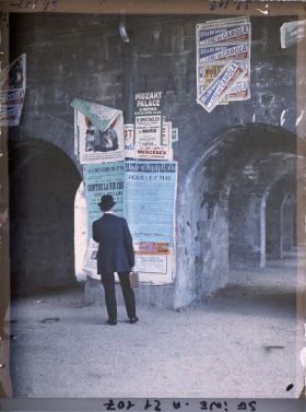 Image représentant Homme lisant des affiches "Contre la vie chère" et du parti socialiste français, à l'occasion du 1er mai, sous la gare d'Auteuil, boulevard Exelmans
