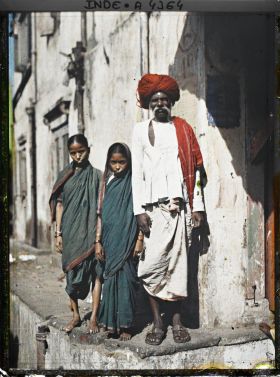 Image représentant Un homme et deux fillettes dans une rue