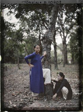 Image représentant Deux jeunes femmes saïgonnaises, l'une en bleu, l'autre en tunique noire, au pied d'un arbre