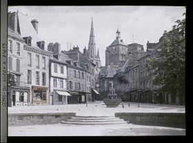 Image représentant La place du Centre avec la fontaine dite "la Plomée" ; à l'arrière-plan, la basilique Notre-Dame-de-Bon-Secours
