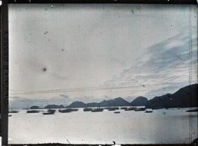 Image représentant Une flottille de sampans et de jonques sur fond de rochers devant l'île Cat-bà, près du poste de douane